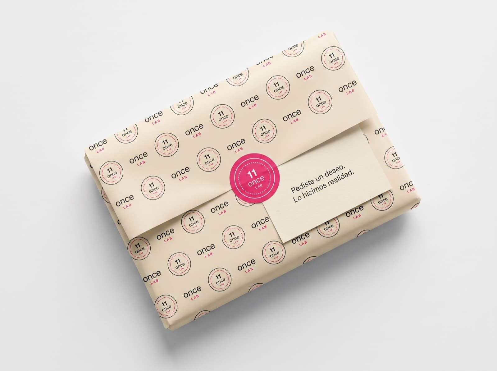 Paquete envuelto en papel de seda crema con un patrón de sellos y una etiqueta rosa.