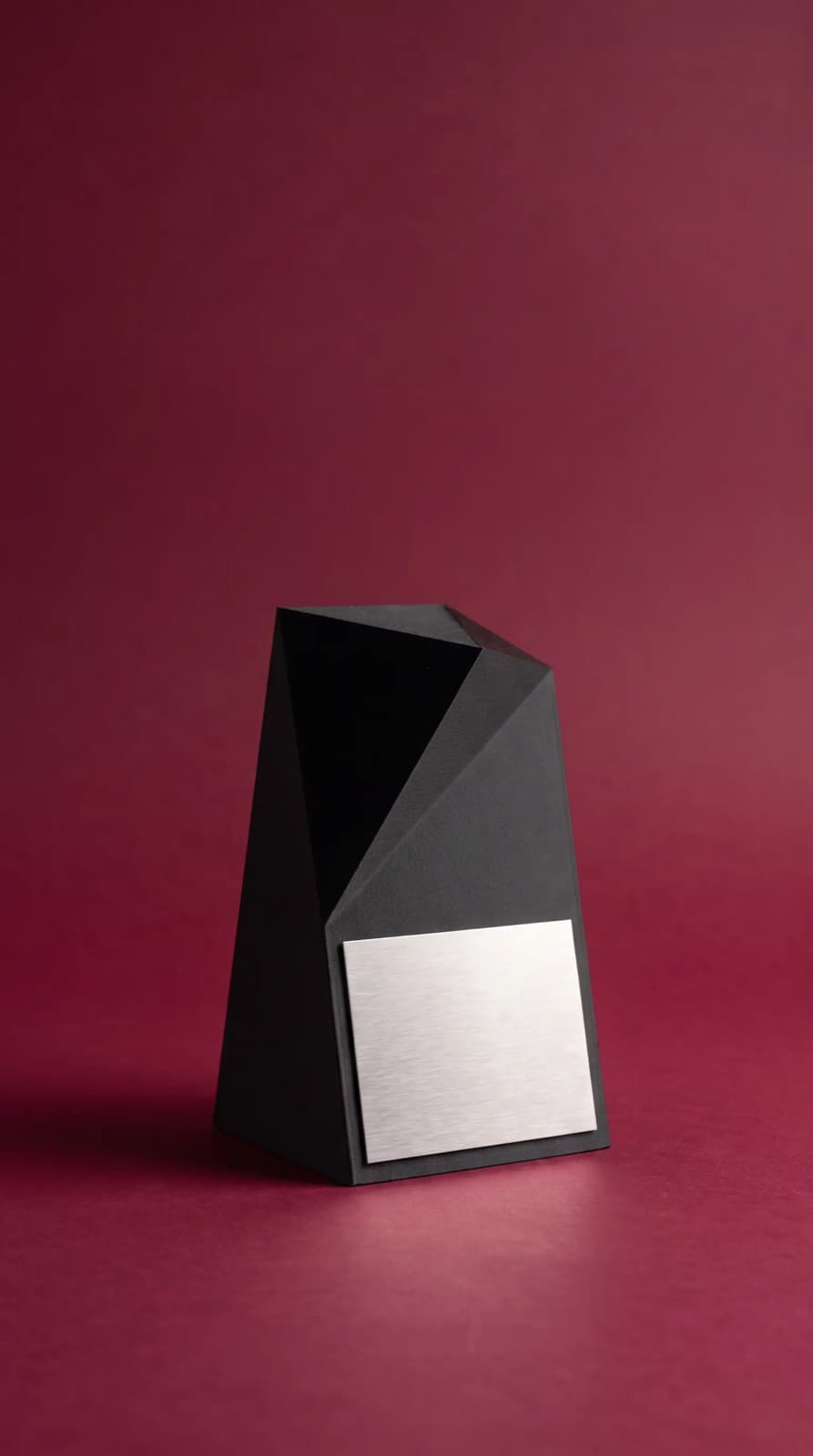 Trofeo negro facetado con placa plateada.